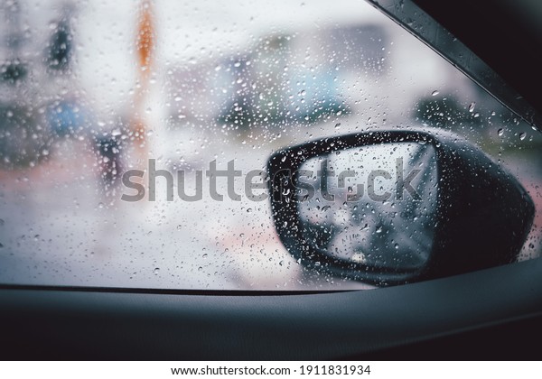 Outside view the fall rain make water\
droplets through the car and rear view\
mirror.