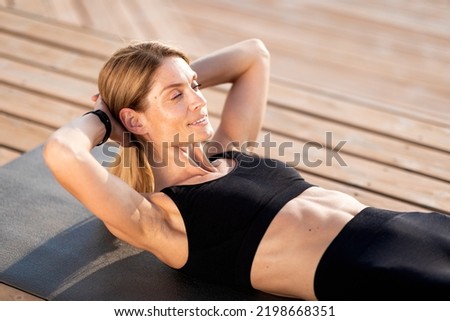 Outside Workout. Smiling Middle Aged Woman Making Abs Crunches Exercise Outdoors, Closeup Shot Of Beautiful Sporty Female Training On Yoga Mat On Wooden Pier, Working Out Abdominal Muscles