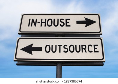 Outsource versus in-house road sign with two arrows on blue sky background. White two streets sign with arrows on metal pole. Directional sign.