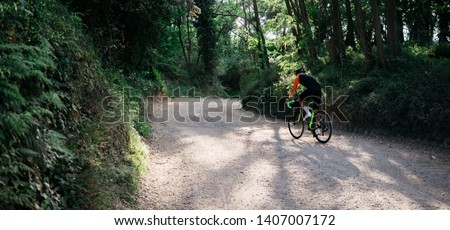 outstanding image in hight resolution of male cyclist rides gravel bike cross country in the forest. man cycling in the nature.  place for text, space for logo and advertisement 