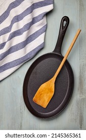 Oval Cast Iron Frying Pan With A Wooden Spatula And A Tea Towel. Mockup For Laying Out Food