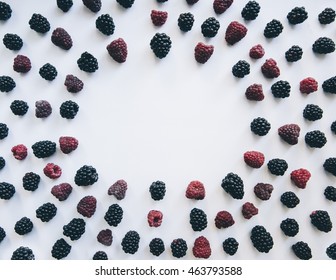 Oval frame made of delicious fresh summer blackberries and raspberries. Minimalism flat lay on the white table background
