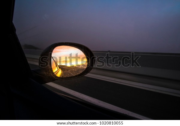 oval mirror car on a highway road on a dark\
sunset evening