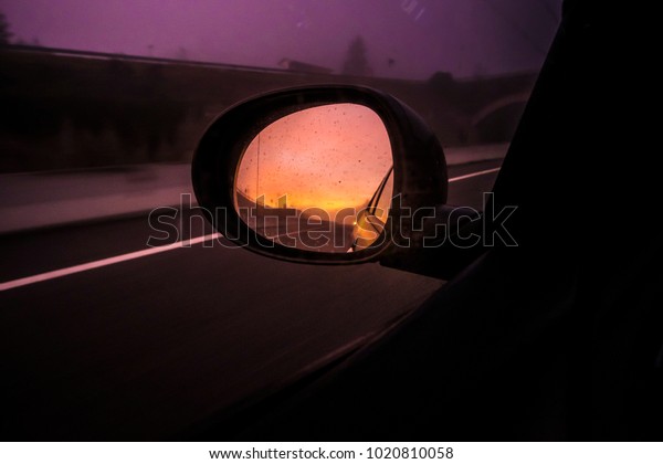 oval mirror car on a highway road on a dark\
sunset evening