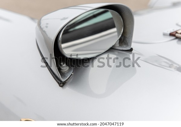 Oval shaped rear view mirror gives driver\
of this vintage car a look at what\'s\
behind.