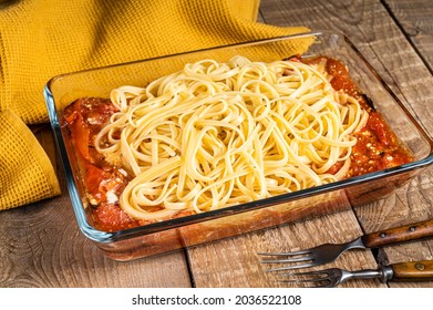 Oven baked feta Spaghetti pasta in baking dish. Wooden background. Top view
