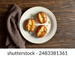 Oven baked potato with butter on white plate over wooden background. Top view, flat lay