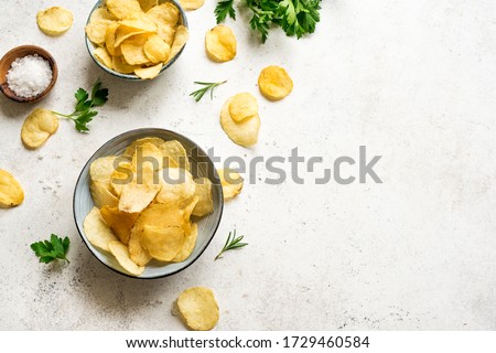 Oven baked  potato chips in bowls. Homemade crispy potato chips on white background, top view, copy space.