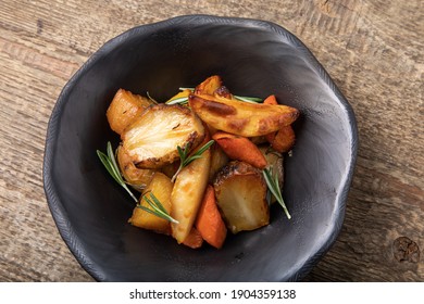 Oven Baked Root Vegetables In Handmade Black Clay Bowl, On Wooden Background