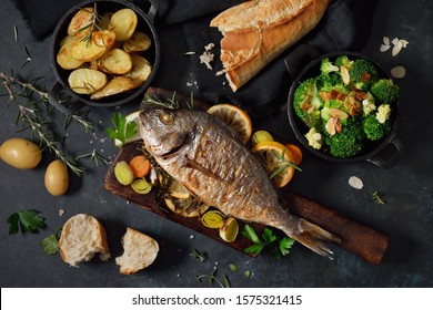 Oven fresh gilthead baked with herbs and lemon, served with potatoes and buttered broccoli with almond flakes