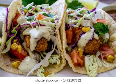 Oven Fried Cod Fish Tacos, With Cabbage Tomatoes, Roasted Corn, Avocado-cilantro Sauce And Salsa. Close Up, Head-on Shot