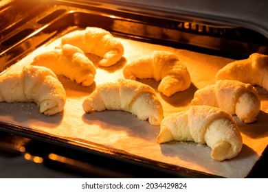 Oven-baked croissants on baking sheet with parchment paper. Sweet bagels baked in hot oven. The process of making curd bagels or croissants - Powered by Shutterstock