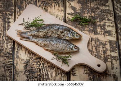 oven-baked fish on the cutting board with a sprig of rosemary