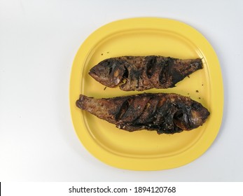 Over cooked burnt fried fish in yellow plate isolated with white. Selective focus. - Shutterstock ID 1894120768