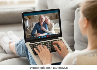Over girl shoulder pc screen view, sit on sofa living in country grandparents communicating with adult granddaughter via videocall. Parents and grownup daughter talking use videoconference app concept - Shutterstock ID 1694685208