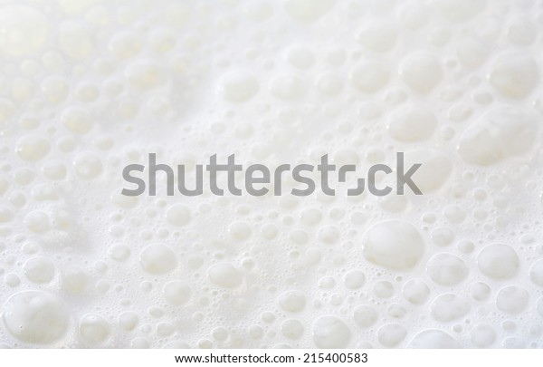 Over head close up full frame background
detail view of frothy white milk creating bubbles, indoors. Macro
still life view of liquid milk
drink.