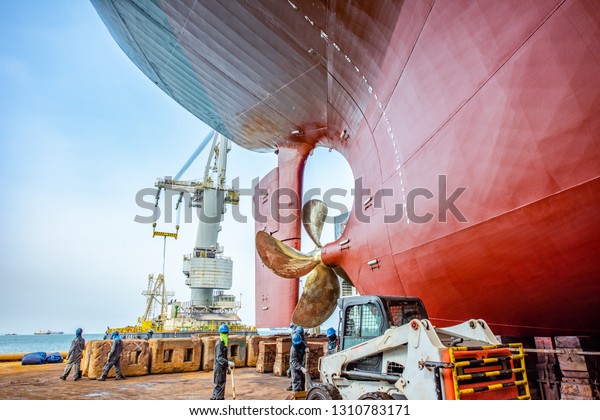 over\
hull dry dock of the commercial ship under repairing, recondition,\
painting and cleaning in dock yard, Aft stern bottom of the ship\
laying on the structure support in floating dry\
dock