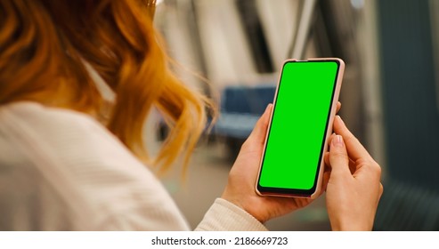 Over the sholder shot woman watching green screen phone on the underground. Woman using technology on the subway. Technology content. - Powered by Shutterstock