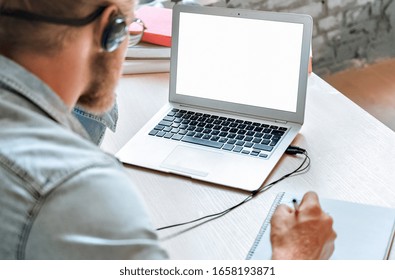 Over shoulder close up man student wear headphones use laptop computer study online listen watch training course make notes e learning teacher call mock up screen, distance education concept. - Shutterstock ID 1658193871