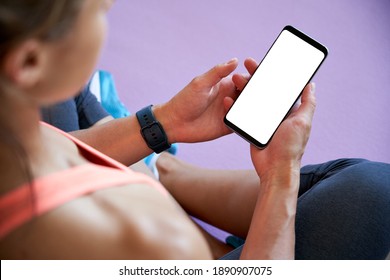 Over Shoulder Closeup View Of Fit Sporty Woman Yoga Teacher Sit On Mat Holding Phone Mock Up Screen Video Calling, Watching Online Workout Training Class Video, Using Fitness App At Home In Gym.