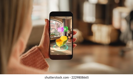 Over the Shoulder Footage of a Female Hand, Holding Smartphone with an Augmented Reality Display Showing a Chair. Woman Doing Online Shopping and Checking her Options In Live Situation In Distance - Powered by Shutterstock