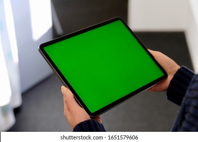 over shoulder of people holding green screen tablet computer. Blur background