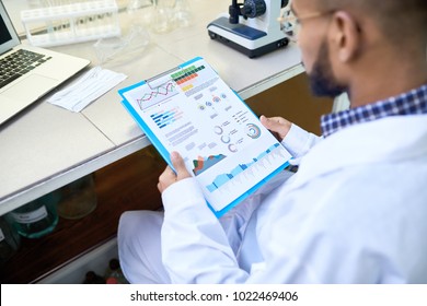 Over Shoulder Portrait Of Young Middle-Eastern Scientist Looking At Data Charts While Working On Medical Research In Laboratory