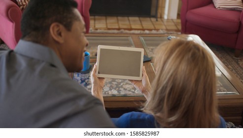 Over The Shoulder Shot Of African American And Caucasian Couple Video Chatting With Daughter And Her Boyfriend. Older Couple Facetiming On Tablet Computer With Children