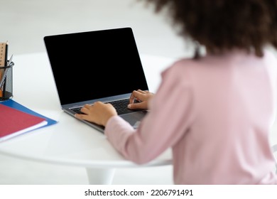 Over Shoulder Shot Of Black Child Preteen Girl With Bushy Hair Sitting At Desk, Using Small Laptop With Black Empty Screen, Unrecognizable Schooler Typing On Computer Keyboard, Mockup