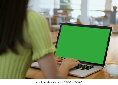 Over The Shoulder Shot Of A Business Woman Working In Office Interior On Pc On Desk, Looking At Green Screen. Office Person Using Laptop Computer With Laptop Green Screen, Sitting At Wooden Table