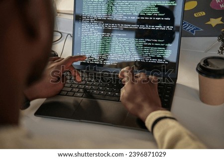 Over the shoulder shot of developer coding on laptop in office