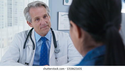 Over The Shoulder Shot Of Doctor Listening To New Patient. Older Caucasian Male Primary Care Provider Talking To Woman About Her Health Care