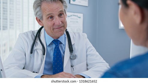 Over The Shoulder Shot Of Doctor Listening To New Patient. Older Caucasian Male Primary Care Provider Talking To Woman About Her Health Care