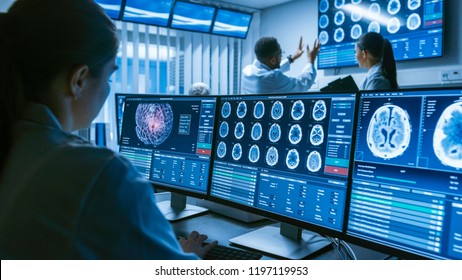 Over the Shoulder Shot of Female Medical Scientist Working with Brain Scan Images on a Personal Computer in Laboratory. Neurological Research Center Working on Curing Brain Tumors.
