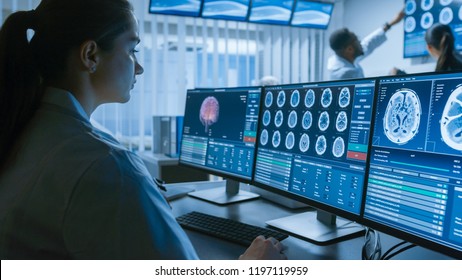 Over The Shoulder Shot Of Female Medical Scientist Working With CT Brain Scan Images On A Personal Computer In Laboratory. Neurologists In Research Center Work On Brain Tumor Cure.