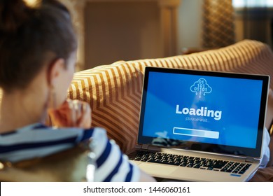 Over Shoulder Shot Of Healthy Woman Laying On Sofa At Modern Home In Sunnny Hot Summer Day Looking At Computer Loading Screen On A Laptop.