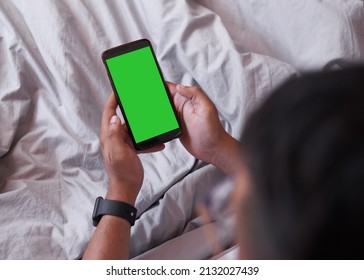 An Over The Shoulder Shot Of A Mobile Phone, Man Sitting In Bed. Chroma Key. High Quality Photo