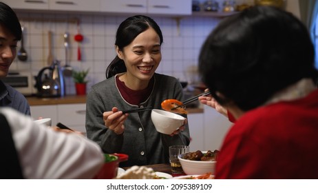 Over Shoulder Shot With Selective Focus Smiling Asian Daughter In Law Receiving Food From Her Senior Mother In The Bowl At Dinner Table On The Eve Of Chinese New Year