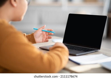 Over Shoulder Shot Of Unrecognizable Chubby Boy With Glasses Sitting At Table And Using Computer With Empty Screen While Doing Homework, Having Video Call With Teacher, Mockup, Closeup