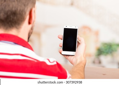 Over The Shoulder Shot Of Young Man Holding Cellphone