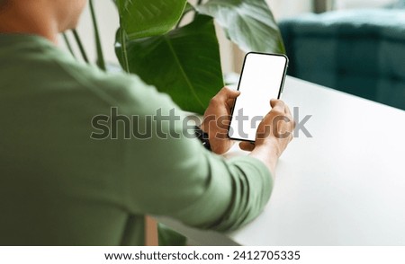 Over shoulder view black guy using phone with white blank screen mockup copy space for mobile app or online offer advertisement, chilling at cafe, cropped shot