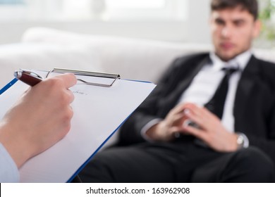 Over the shoulder view, of a business man sit on a couch talking to his psychiatrist - Shutterstock ID 163962908