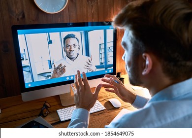 Over Shoulder View Of Caucasian Business Man Talking With African Male Partner On Video Conference Call Discussing Social Distance Work At Virtual Remote Meeting Videoconferencing Using Pc Computer.