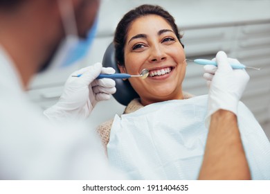 Over the shoulder view of a dental doctor treating female patient. Female having routine dental checkup at dentist. - Shutterstock ID 1911404635