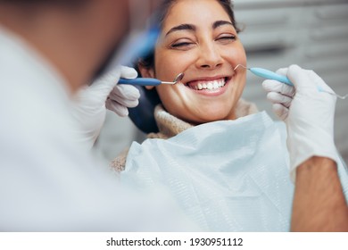 Over the shoulder view of a dentist examining a patients teeth in dental clinic. Female having her teeth examined by a dentist.