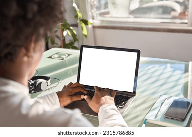 Over shoulder view of gen z African American teen student using laptop mock up white screen template on lap advertising website, digital elearning hybrid education on computer sitting at home table. - Powered by Shutterstock