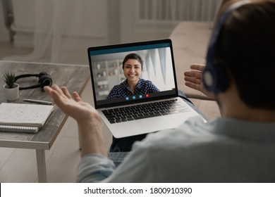 Over shoulder view of man speak talk on video call on laptop with smiling ethnic woman wife, male have webcam virtual digital conference or online business meeting with colleague at home office - Shutterstock ID 1800910390
