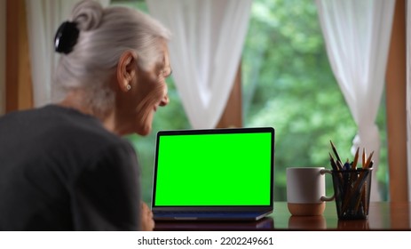 Over shoulder view of smiling senior elderly woman making video call on laptop green screen talking and listening during video chat with friends or colleagues. - Powered by Shutterstock