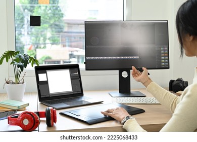 Over Shoulder View Of Video Editor Editing Video Footage On Personal Computer At Her Workstation