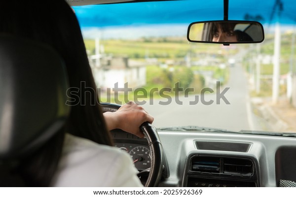 over the shoulder view of Woman driving the\
vehicle, concept of driver in the\
city